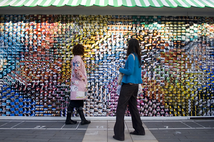 a couple of women standing in front of a wall covered in colorful ons