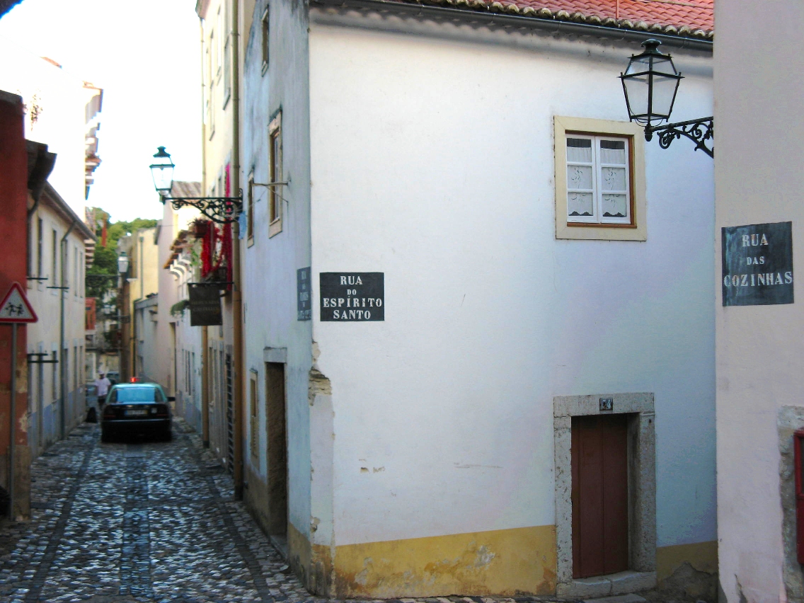 a narrow cobblestone road with several signs on it