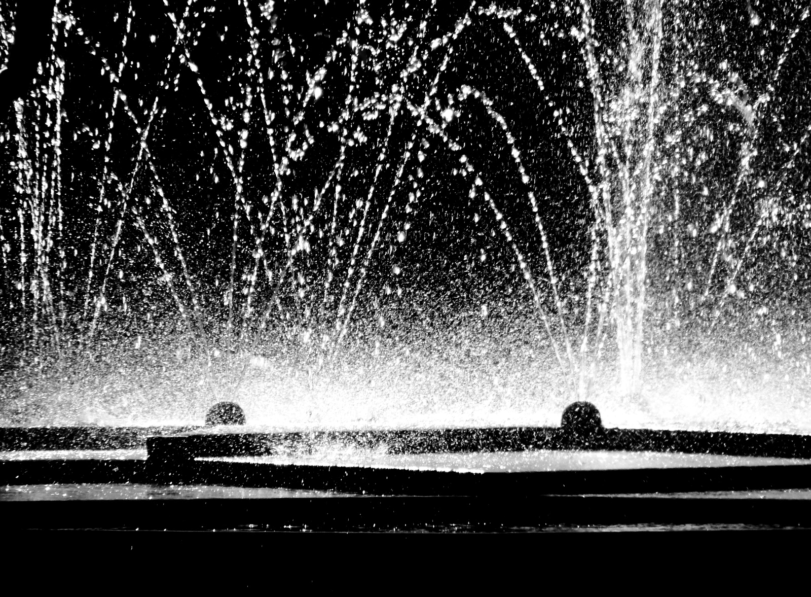 a black and white image of fireworks shooting in the sky