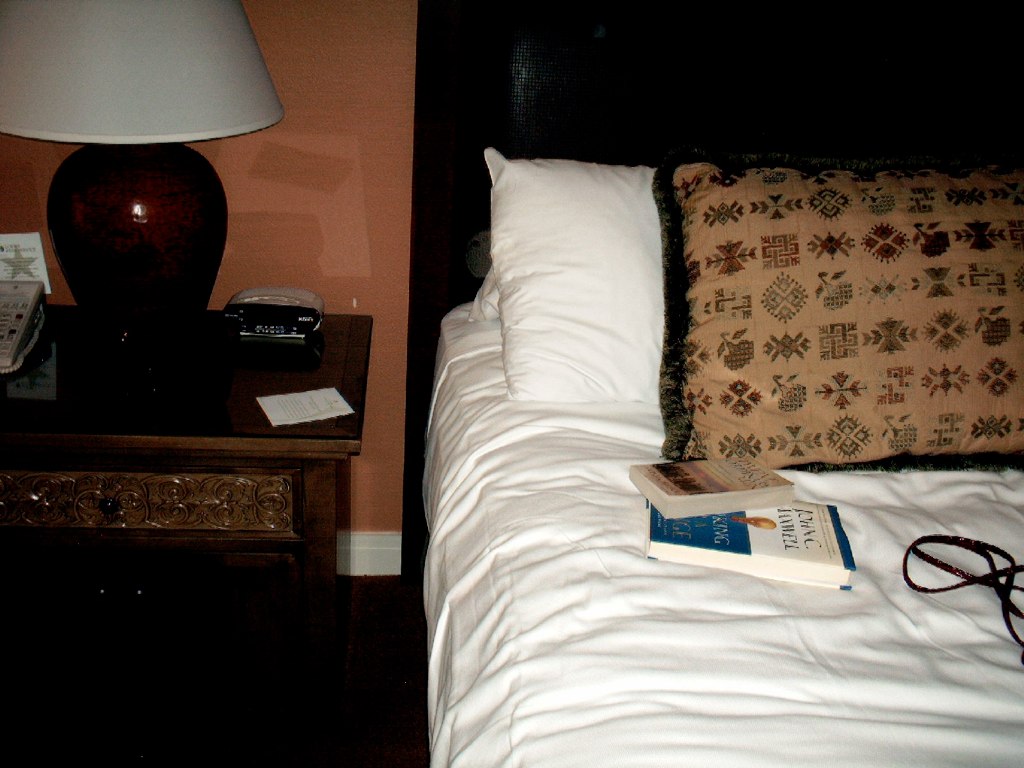 a bed with a headboard, night stand and pillow on it