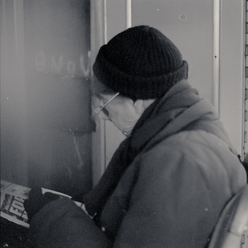 a man wearing glasses and hat reads a book