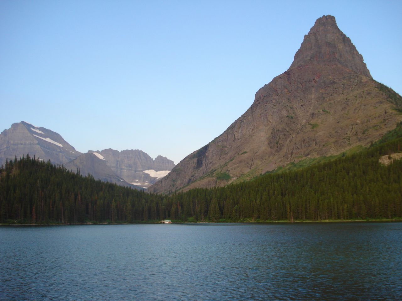 a mountain range towering above a lake and forest