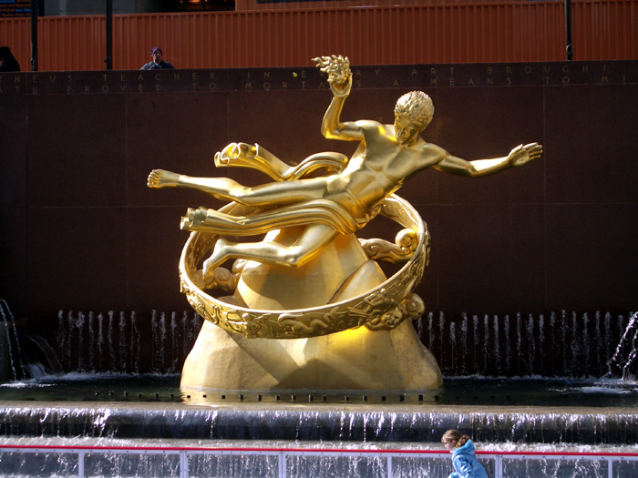 the statue shows two women and a man in motion on an intricate ring with fountains
