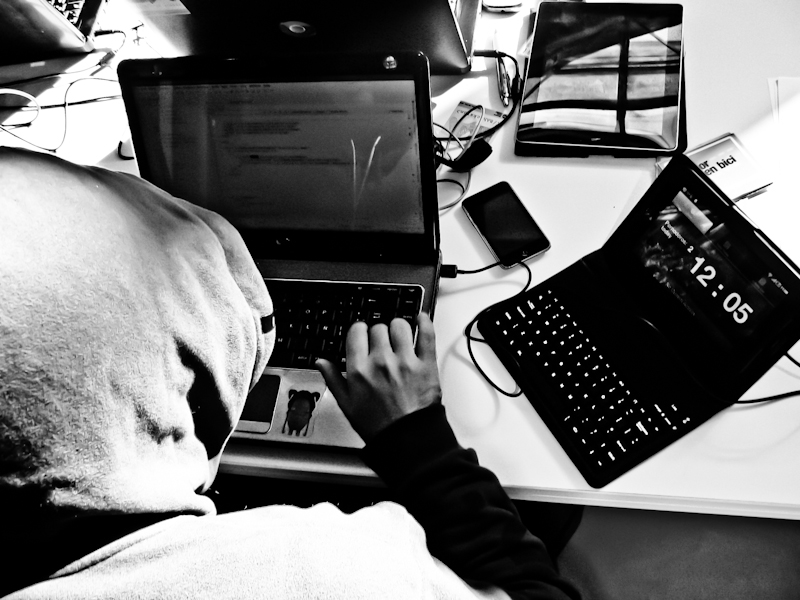 a person with hood up using a laptop at a desk