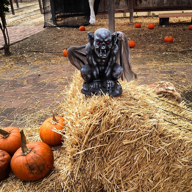 a statue of a vampire sitting on hay with some pumpkins