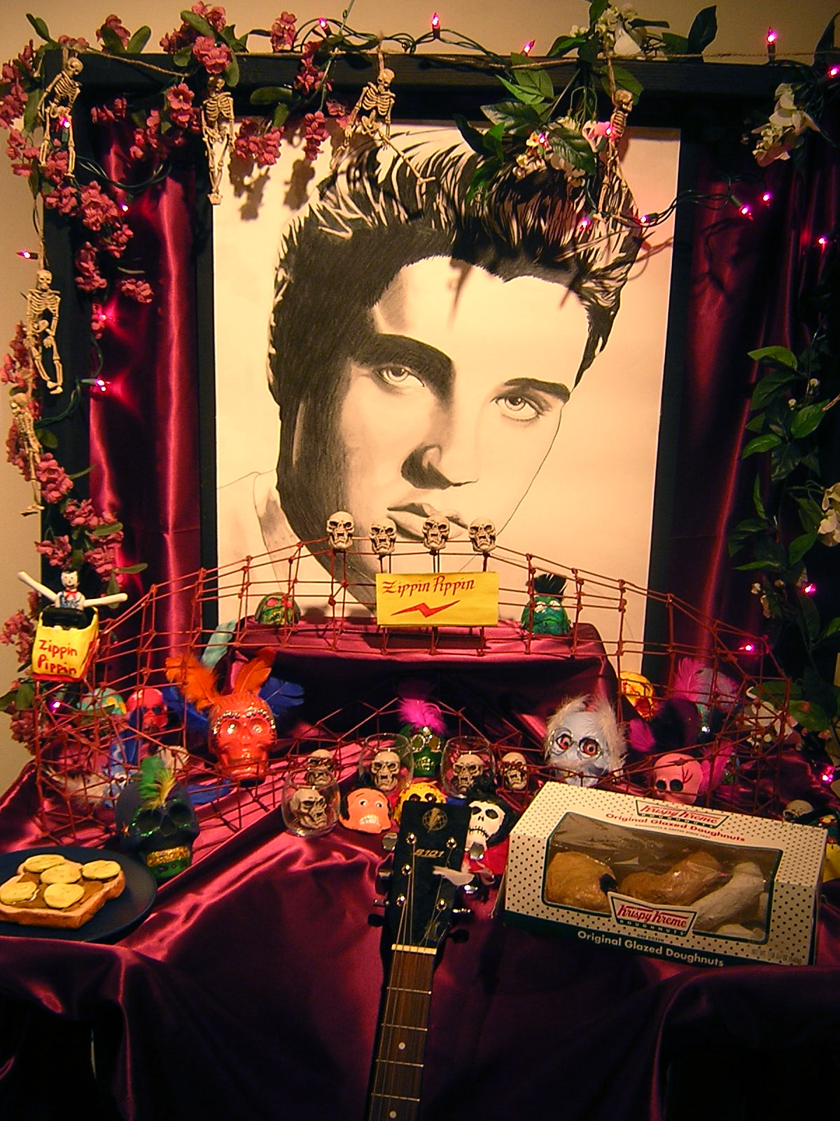 a table topped with a guitar, cake and a painting of elvis