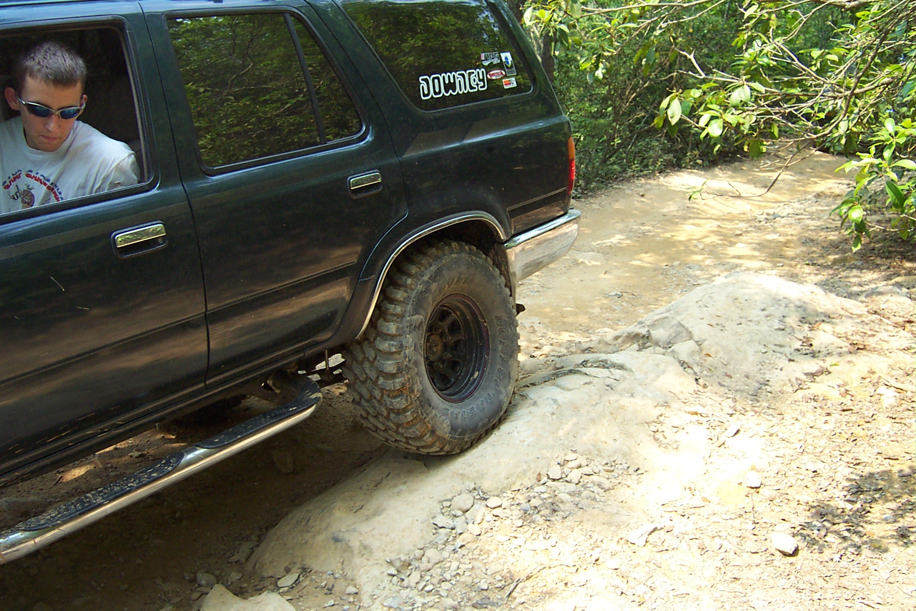 a young man sits in the back of a vehicle with his jeep up close