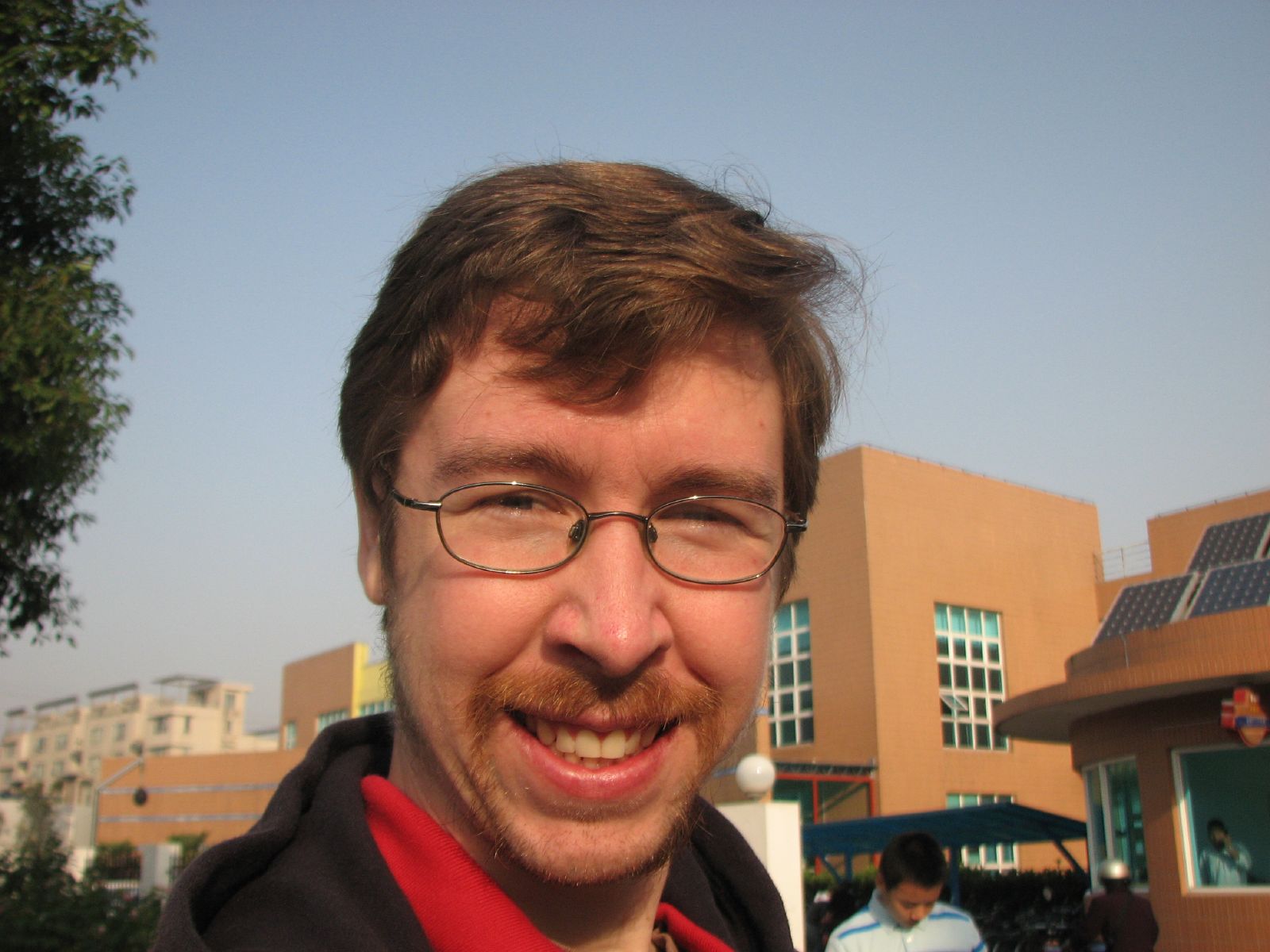 a man with glasses is smiling in front of a building