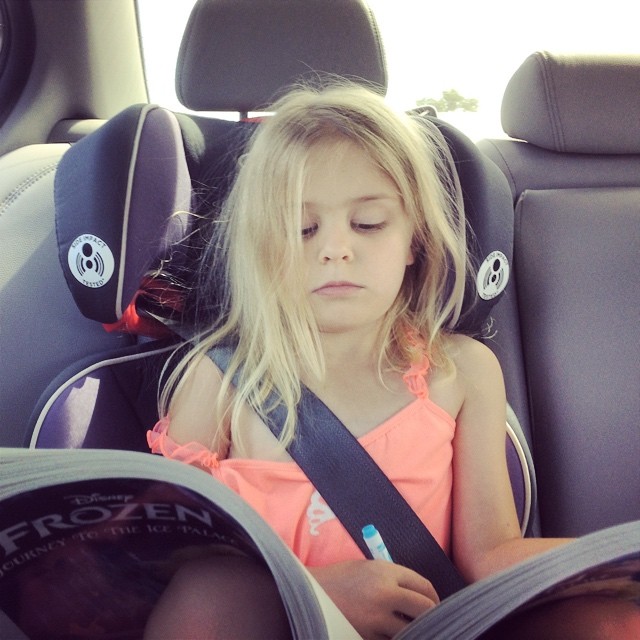 a  sitting in a car seat reading a book