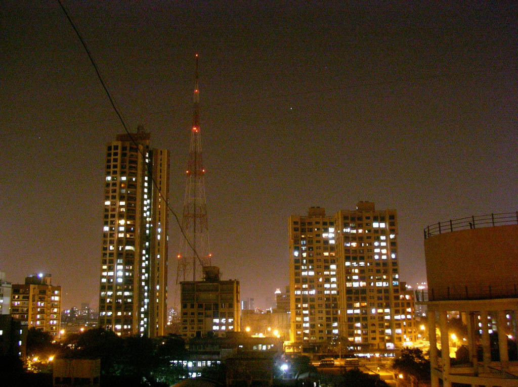 a city skyline at night with a tv tower at the top