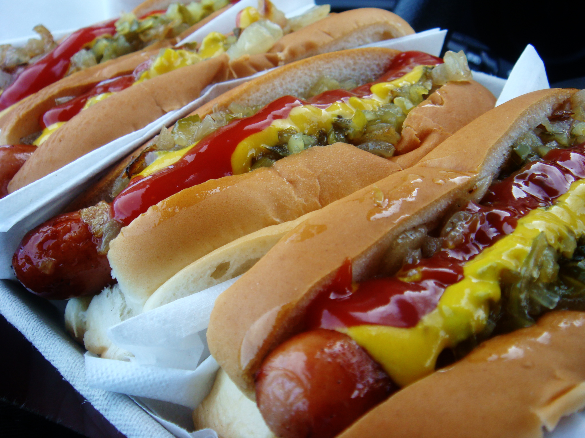 six long dogs with condiments lined up