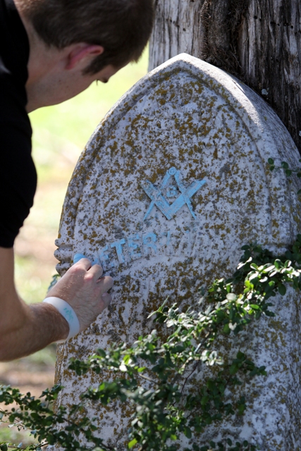 a man bends down to pet the writing on a large stone