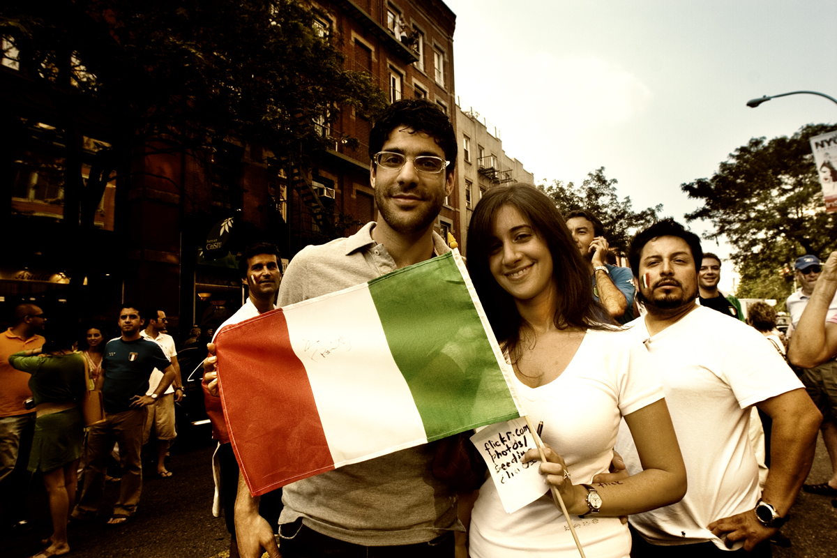 a man holding up a small flag as a woman holds a sign with her face and arms