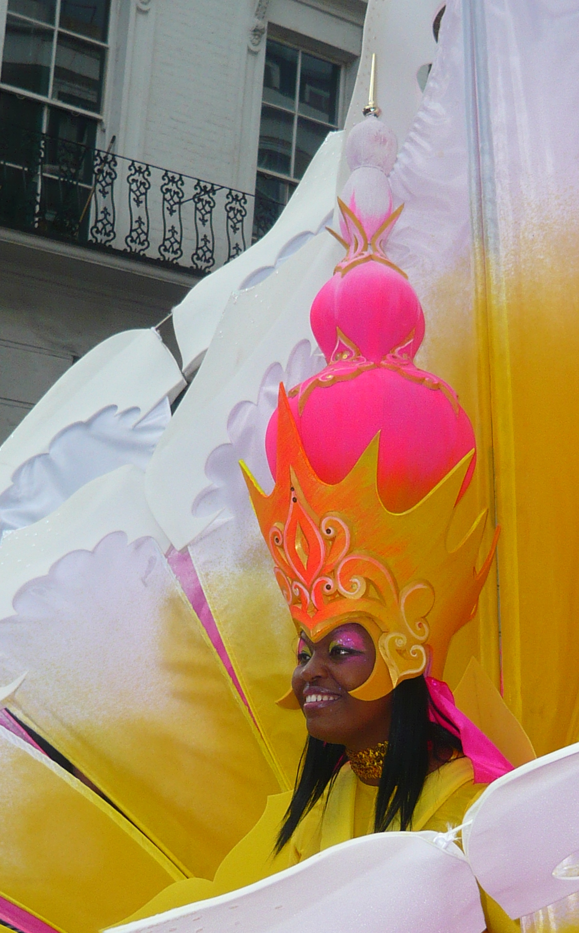 a woman in costume stands behind a float that looks like a large orange and pink ball