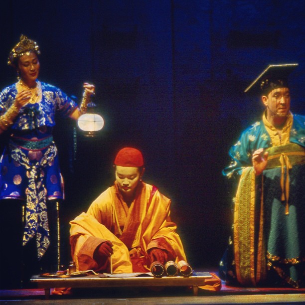 four people in oriental costumes sitting on a stage