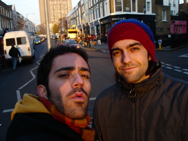 two men standing next to each other on the street