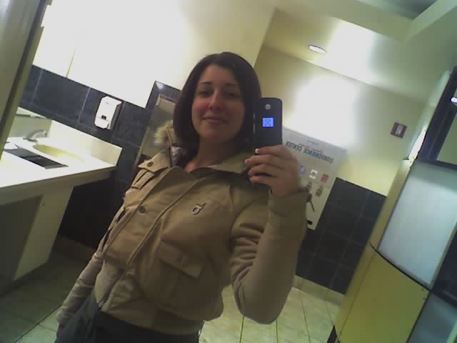 a woman taking a selfie in the mirror in a restroom