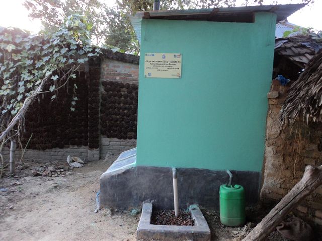 a small building in the dirt with a green tank and fire extinguisher