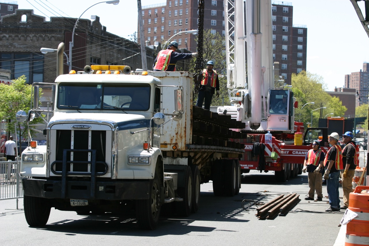 men work on construction equipment behind a truck