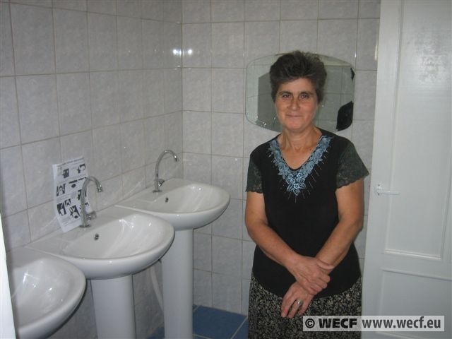 woman in bathroom posing next to two white sinks