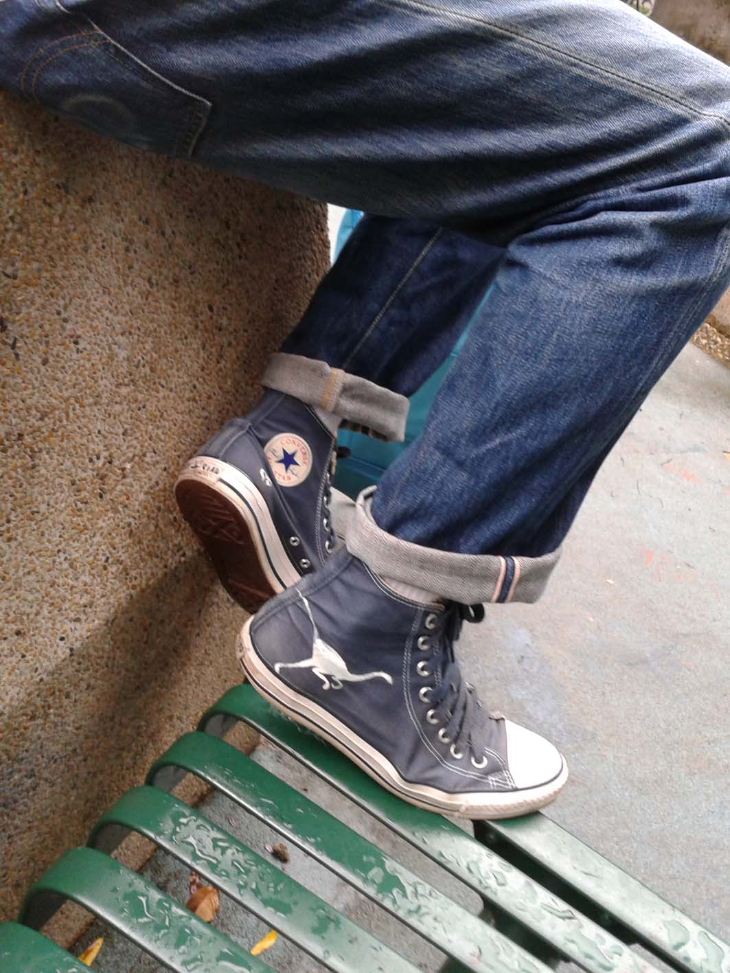 a person sitting on a bench with sneakers on