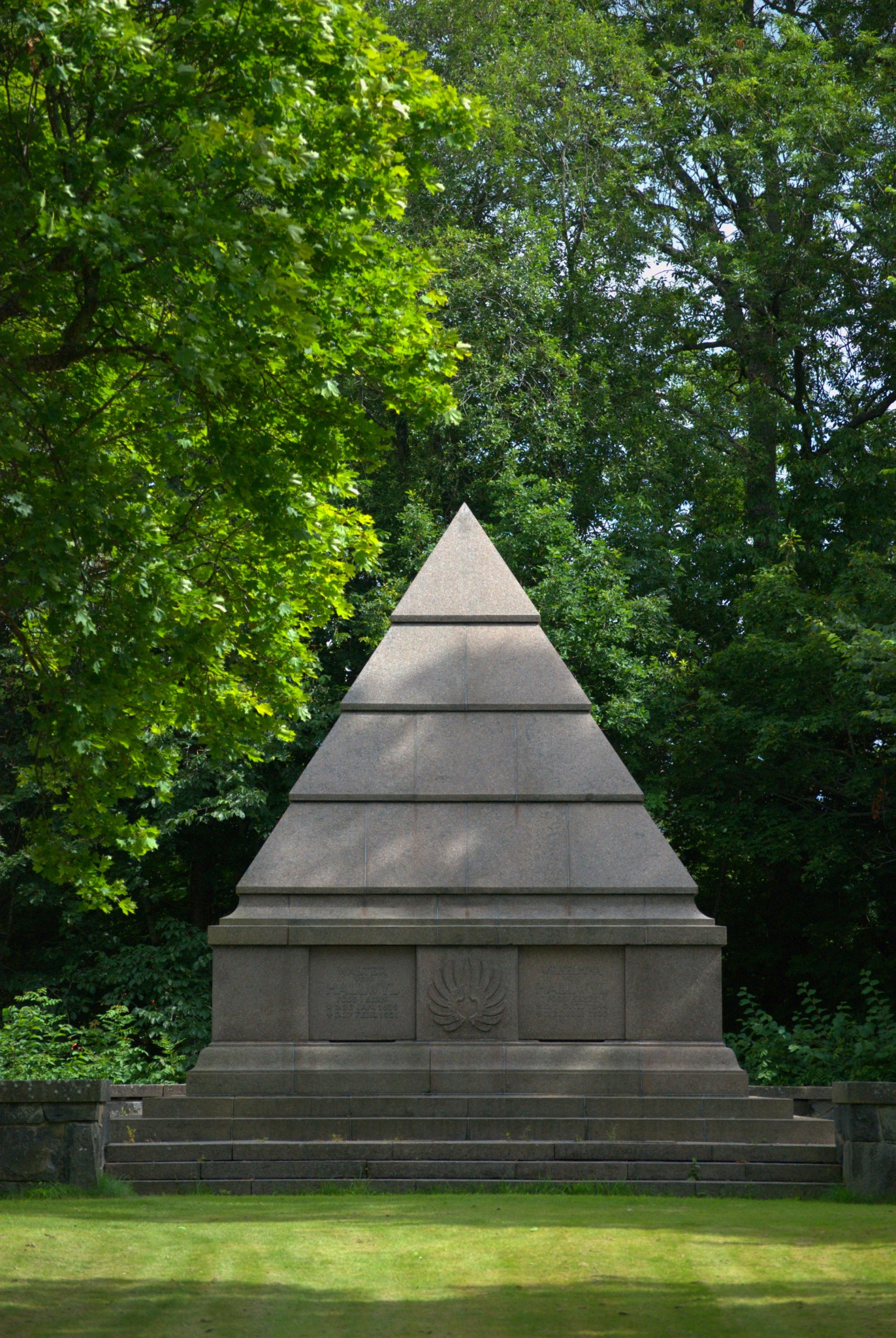 a monument in a grassy area surrounded by trees