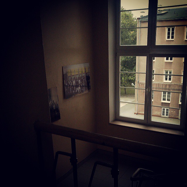 a window in an apartment with some buildings and a chair in the foreground