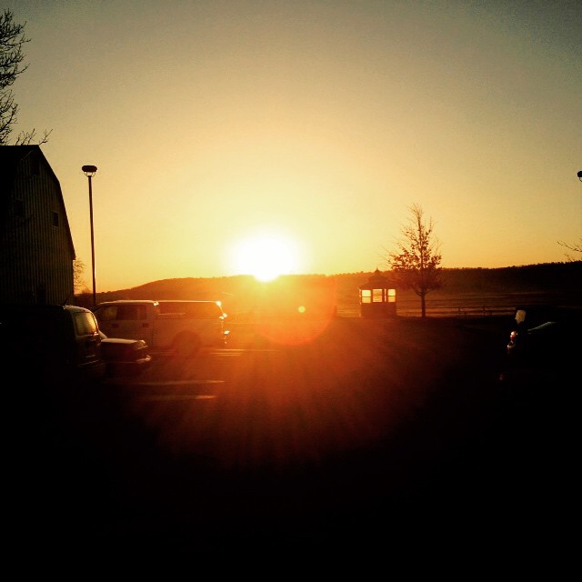 cars are parked on the lot as the sun sets