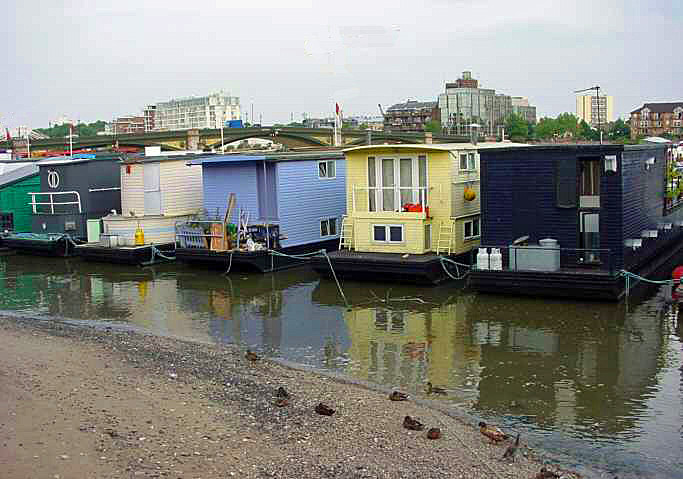 two houses sitting next to a river with boats