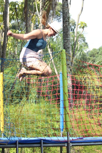 a woman jumps on a trampoline during an outdoor obstacle event