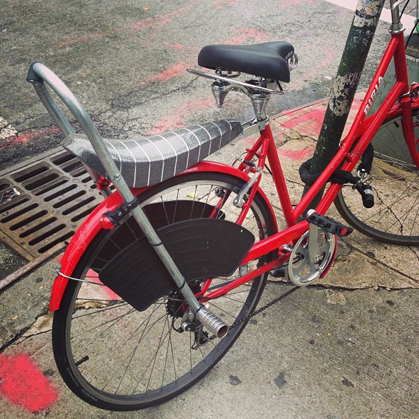 a red bicycle is parked next to the sidewalk