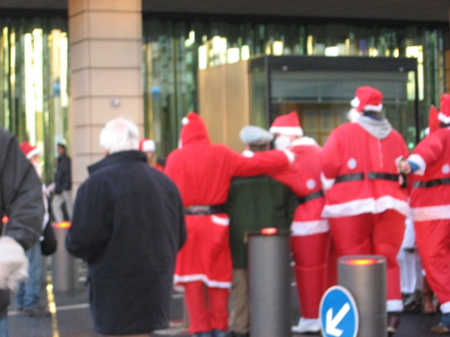 people dressed in santa claus costumes gather outside a building