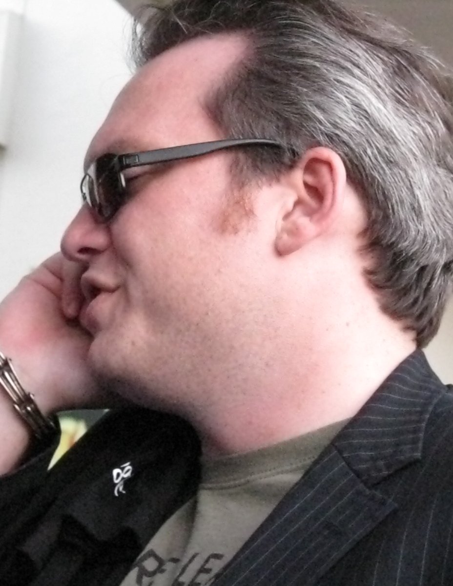 a man with sunglasses and a pinstripe blazer on while talking on the phone