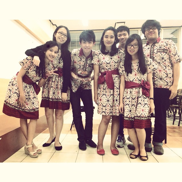 an asian group poses in matching clothing, one of which is holding a camera
