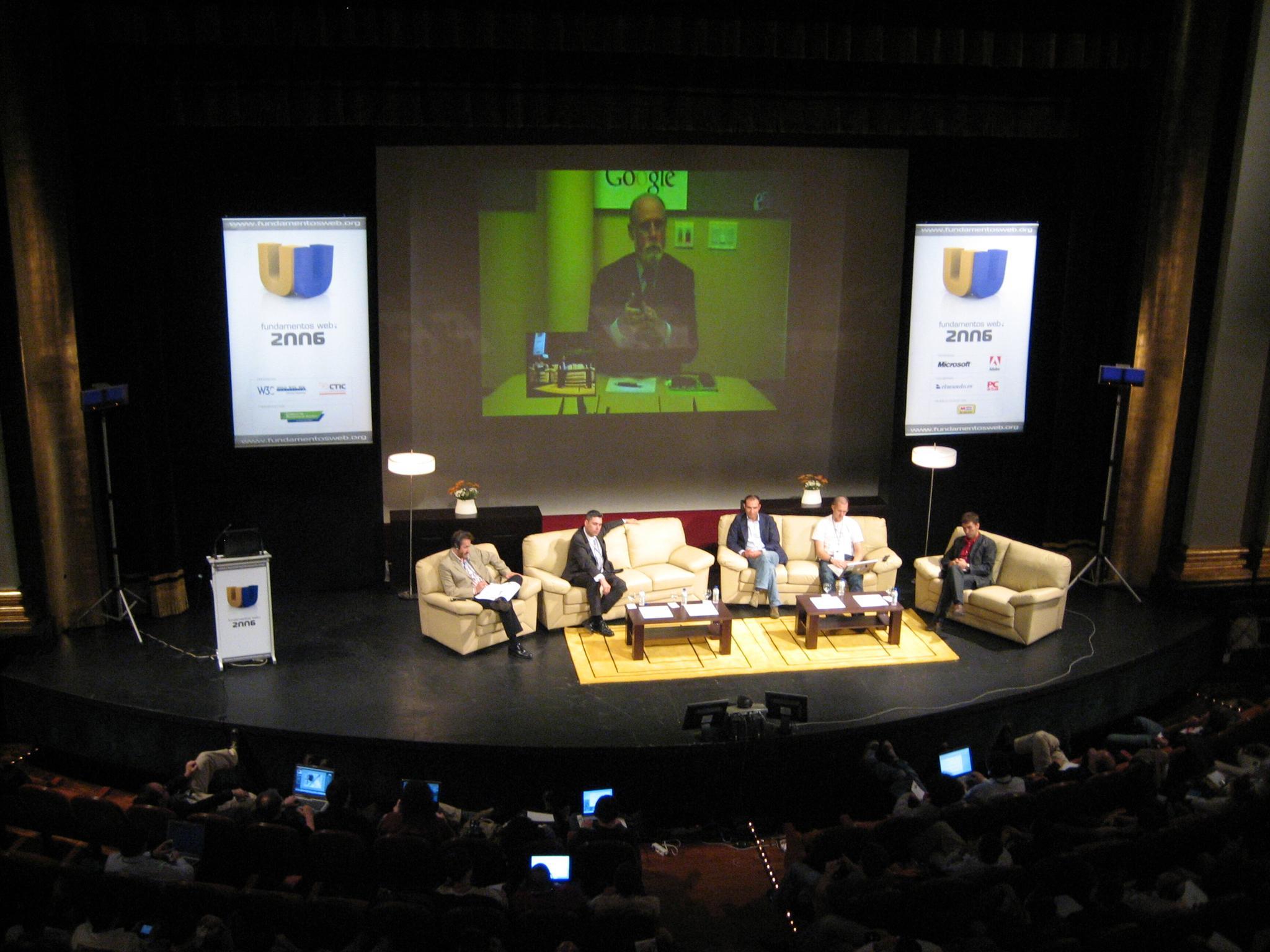 several people sit on chairs in a dimly lit stage