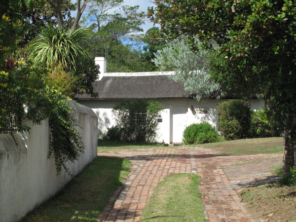 a walkway leads to a small house with a thatched roof