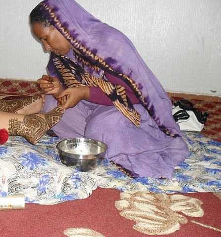 an indian woman doing her skin tattoo in the bedroom