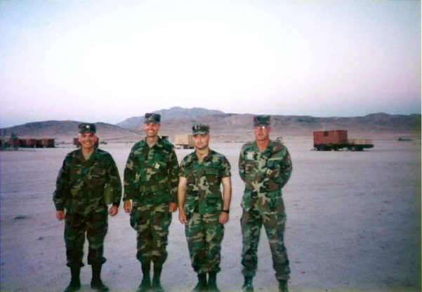 four soldiers pose for a pograph in the desert