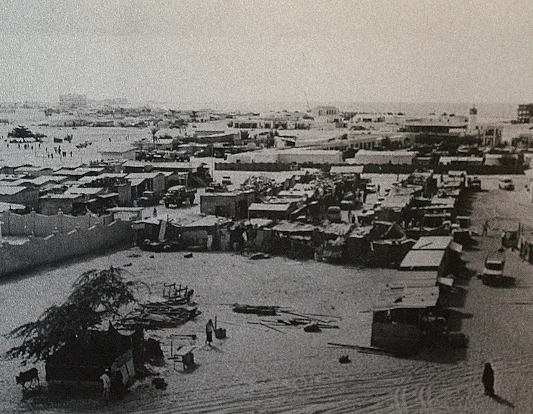 an old pograph of a beach with sand and shacks