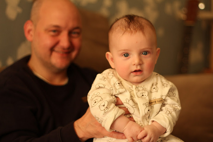 man with bald head and a blue eyes holding his infant boy