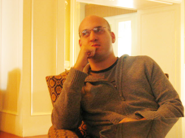 a man in glasses sits in the middle of the room and looks up