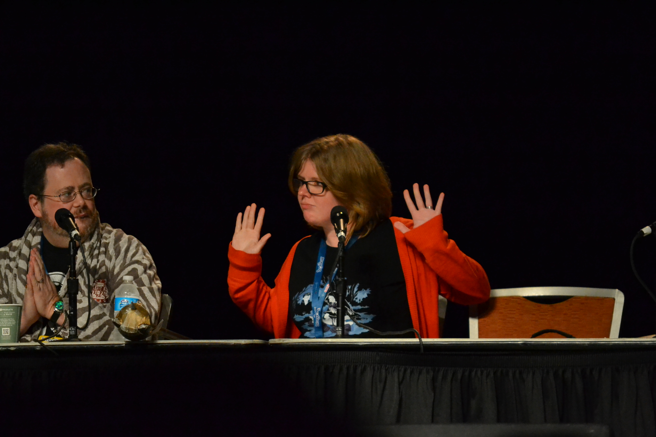 two people sitting at a table with a microphone