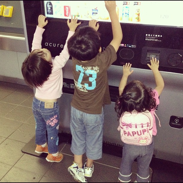 three children standing near an interactive flat screen tv