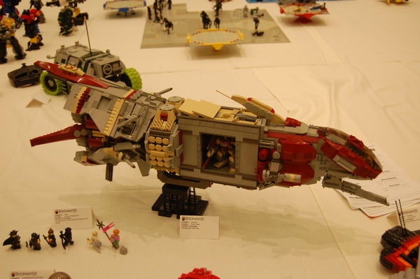 people standing around a model jet made from legos