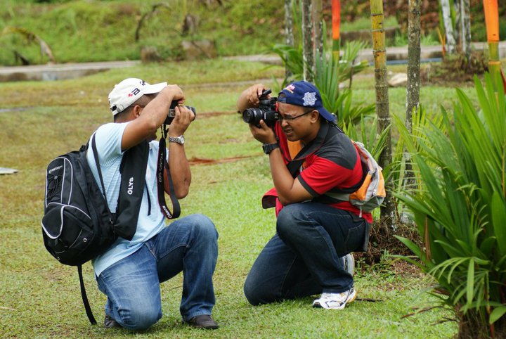 two people with cameras taking pictures on grass