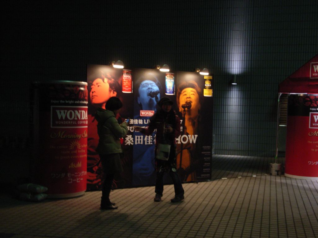 two young men stand near three red colored displays