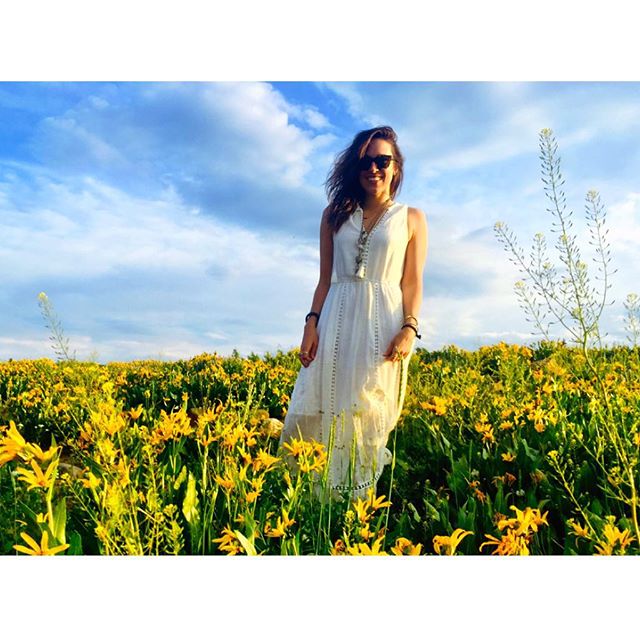a beautiful woman standing in a field full of flowers