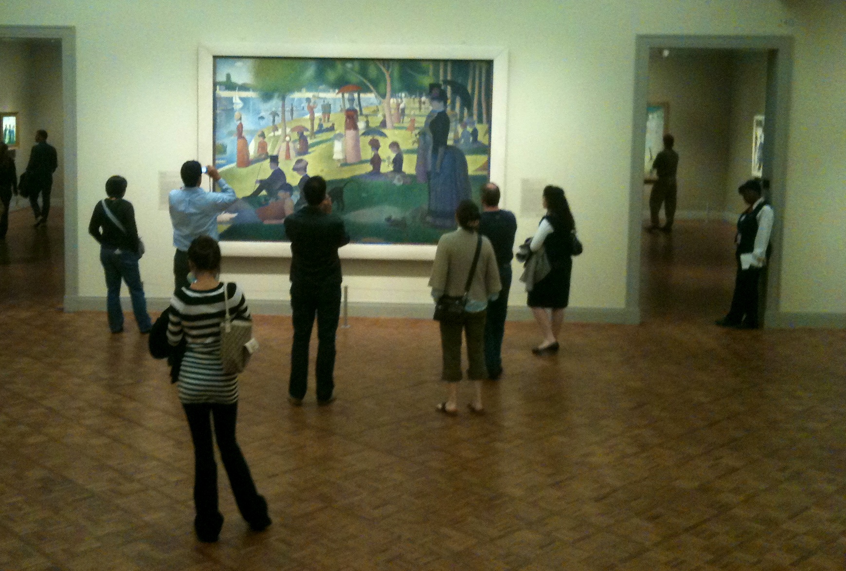 several people are standing in an art gallery looking at a painting