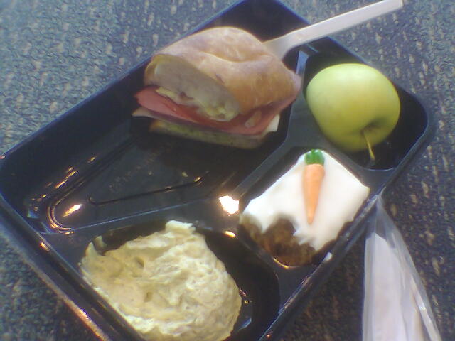 a plastic tray topped with sandwiches and apples