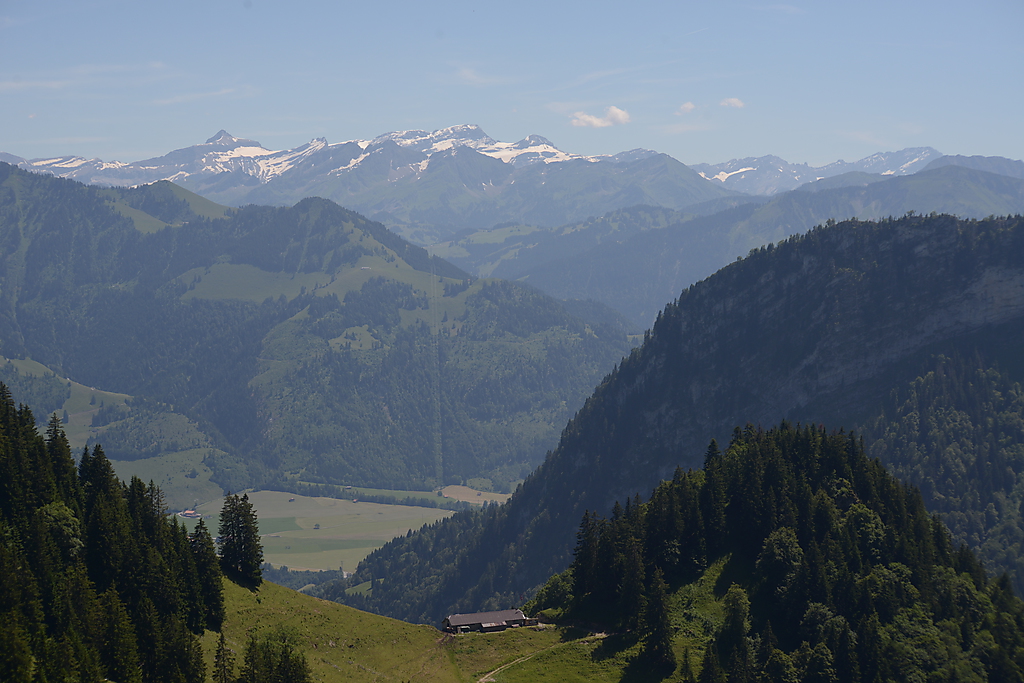 view from above of mountains with a dirt path to a hut